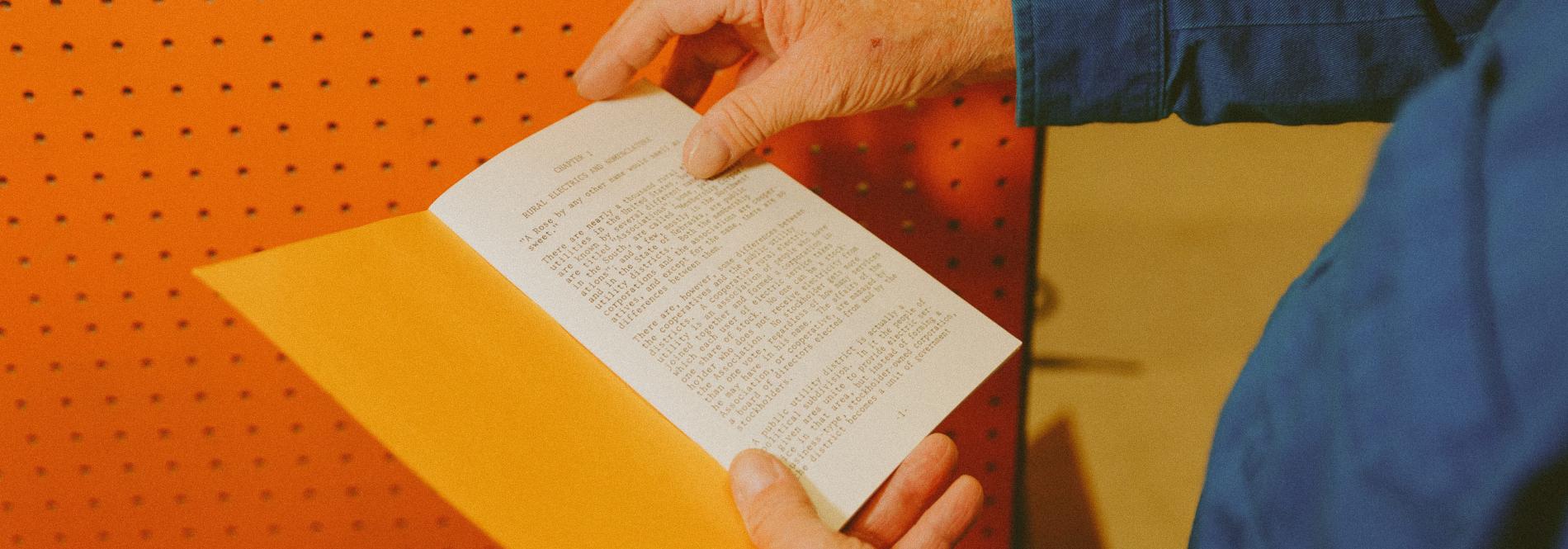 A hand holding a booklet