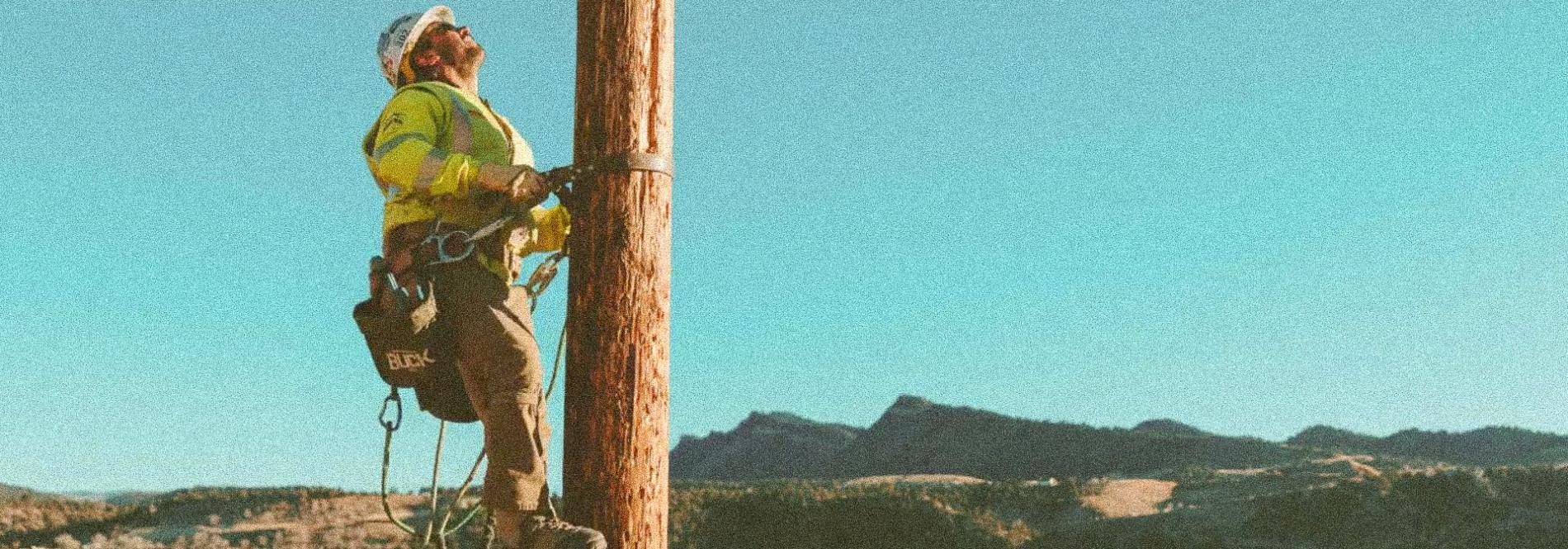 A lineworker climbs a power pole