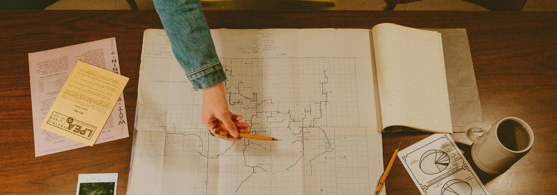 A person gestures to a map with a pencil