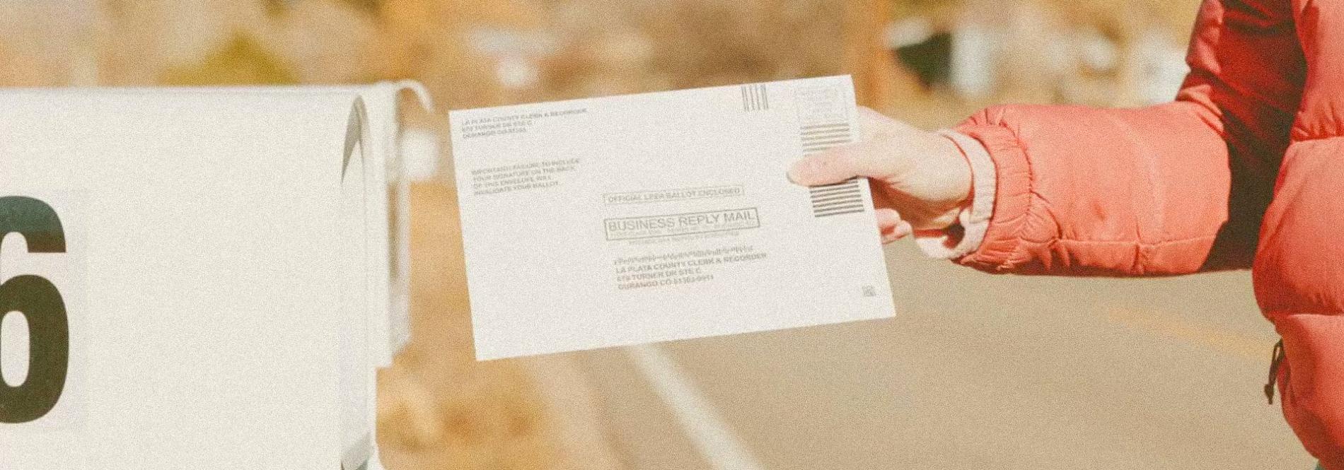 A person puts a ballot in the mailbox