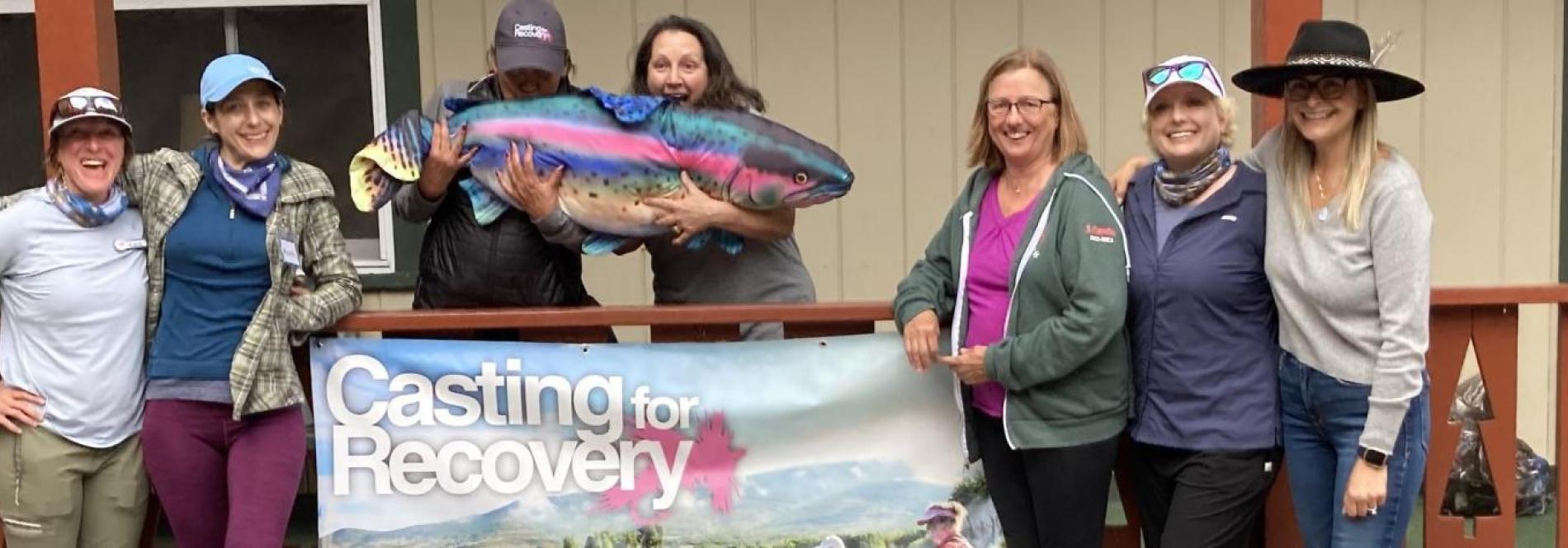 People gather round a casting for recovery banner