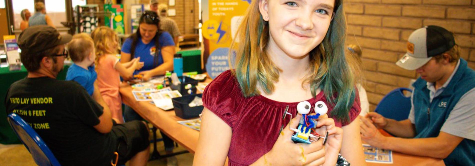 Young person holds a robot they created at the La Plata County Fair with LPEA